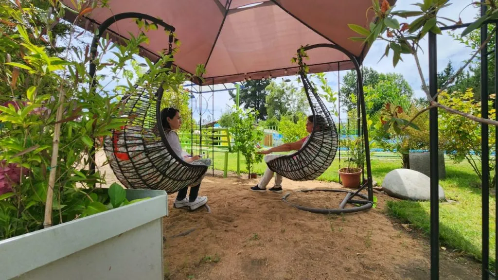 Fachada cabaña roja con enredaderas y jardineras en Los Nogales 2
